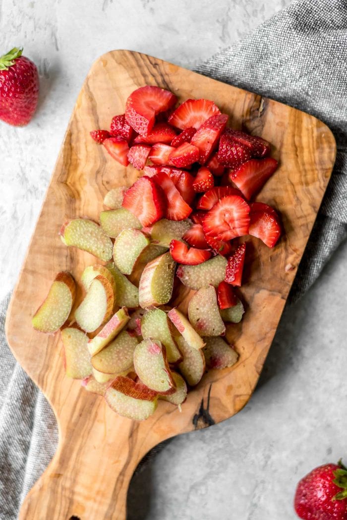 Chopped fresh rhubarb and strawberries on a cutting board.