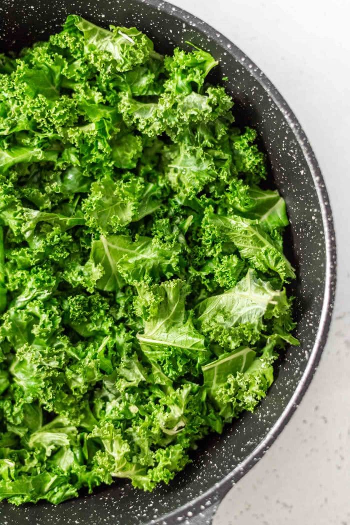Cooked chopped kale in a black skillet.