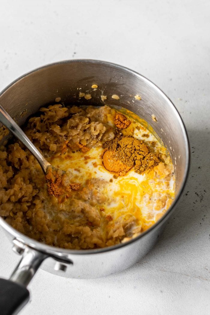 Small saucepan with red lentils, curry powder, turmeric, coconut milk and garlic.