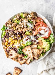 A lentil taco salad with tomato, sour cream and pieces of pita in it.