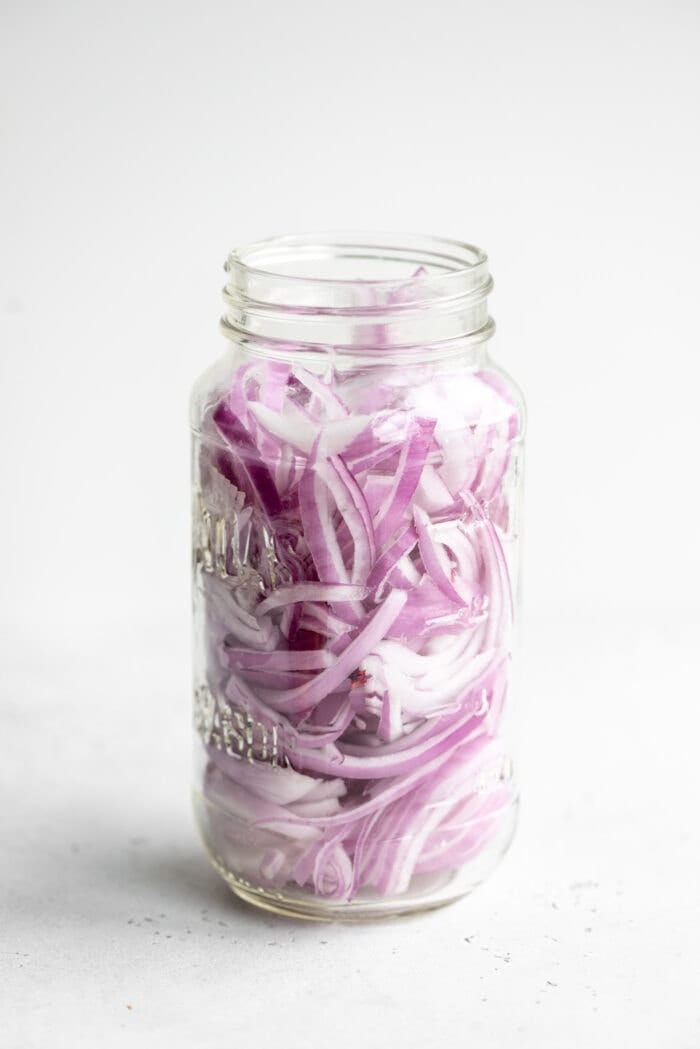 Raw red onion packed into a glass jar.