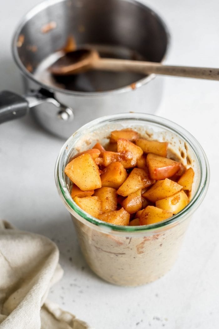 Cooked diced apples in a jar with overnight oats.