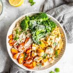 Roasted squash and carrots with red lentils, quinoa, broccoli and tahini sauce in a bowl.