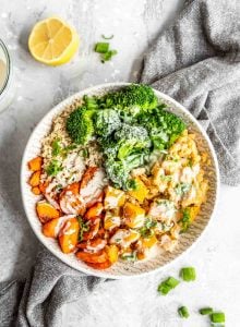 Roasted squash and carrots with red lentils, quinoa, broccoli and tahini sauce in a bowl.