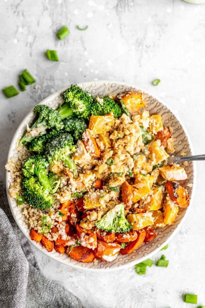 Red lentils, quinoa and roasted vegetables mixed up in a bowl with tahini sauce.