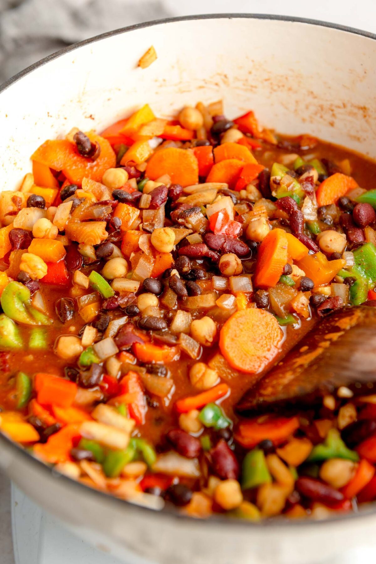 Thick three bean chili with carrots and bell peppers in a large pot.