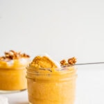 A spoon scooping pumpkin mousse out of a jar.