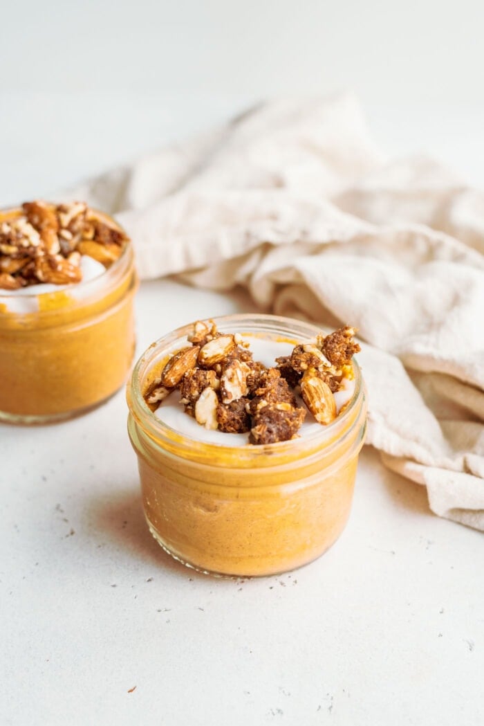 Small jar of pumpkin mousse topped with crumbled pecans.