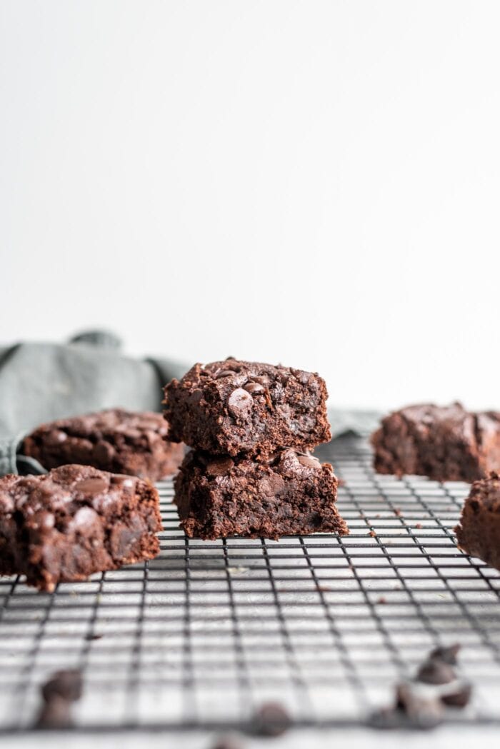Stack of 2 vegan oat flour brownies sitting on a cooling rack.