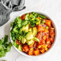 A bowl of sweet potato chili topped with avocado, cilantro and green onion.