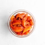 Overhead shot of sliced roasted red peppers in a jar.