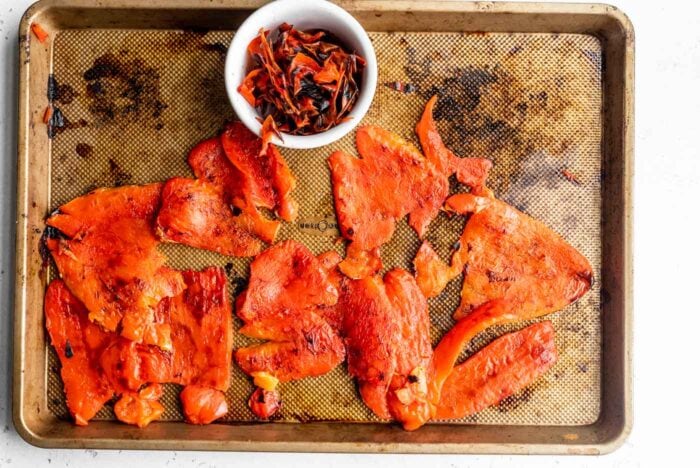 Peeled roasted red peppers on a pan.