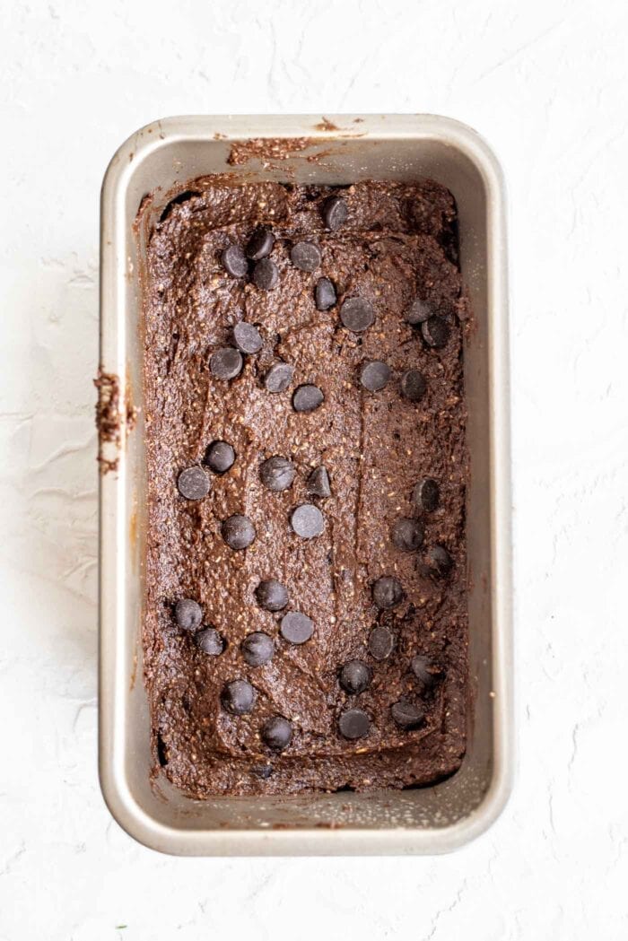 Raw brownie batter with chocolate chips in a loaf pan.