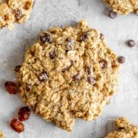 A close up of a oatmeal cookie with raisins and chocolate chips.