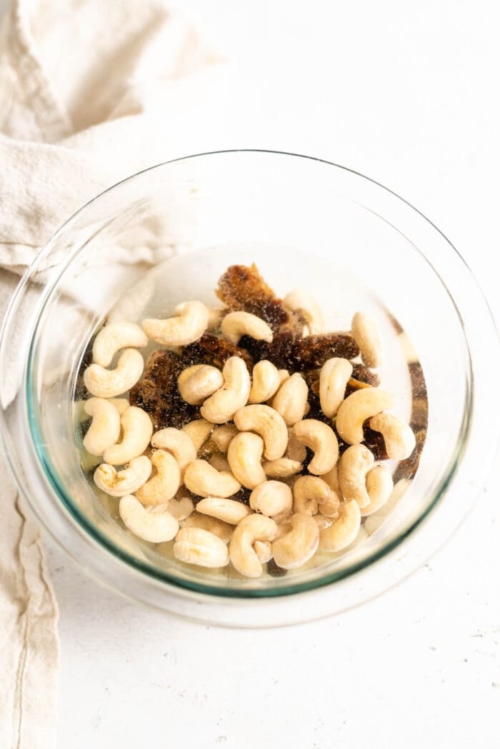 Cashews and dates in a glass bowl of water.