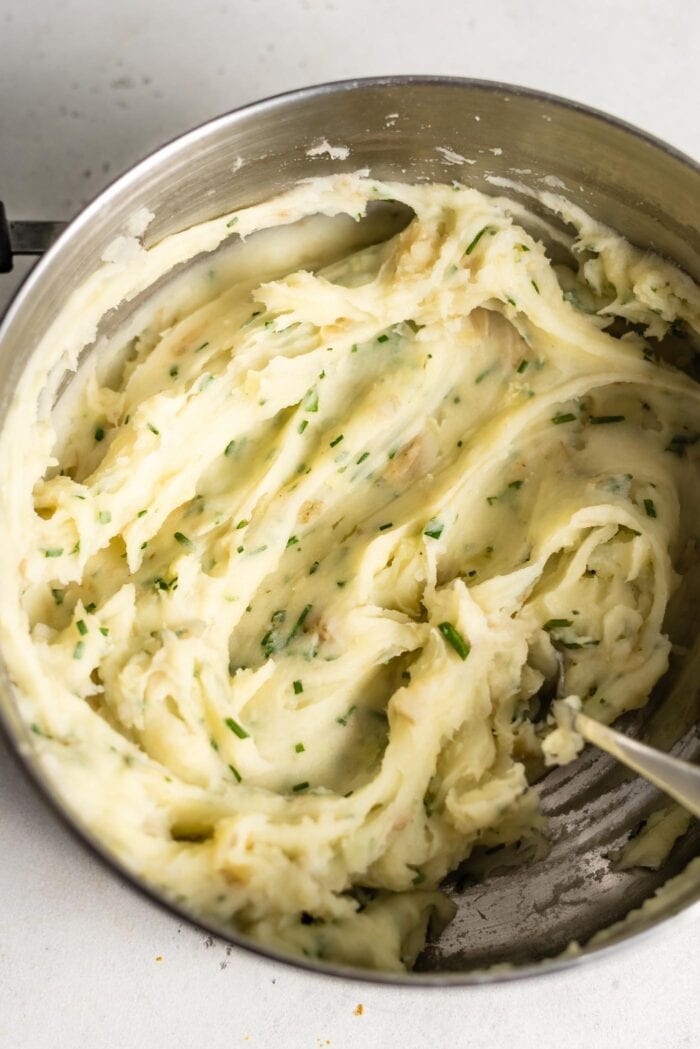 Mashed potatoes with fresh chives in a large pot.