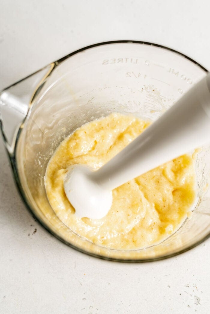 Mashed banana in a bowl with an immersion blender.