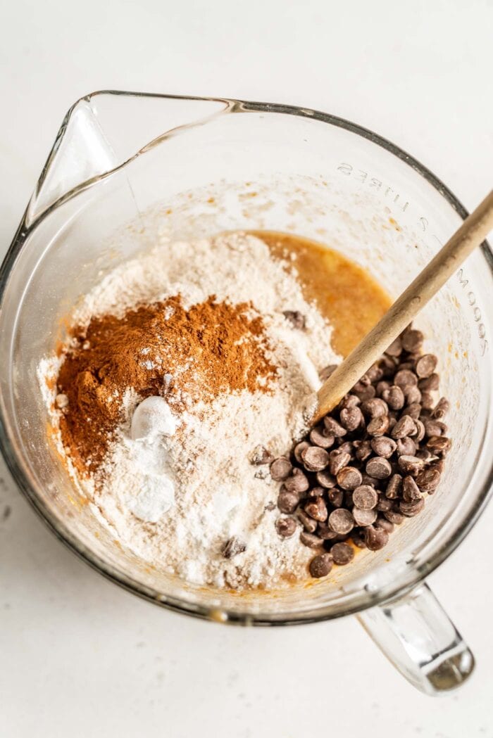 Flour, cinnamon, baking powder and chocolate chips in a glass mixing bowl.