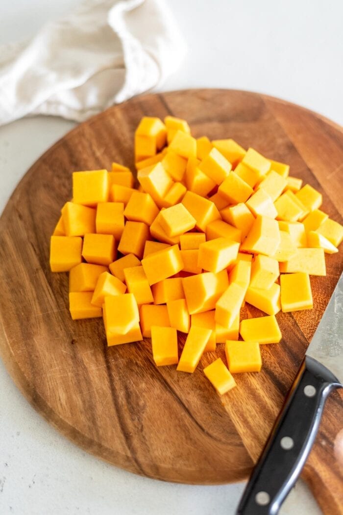 3 cups of peeled and cubed butternut squash on a cutting board with a knife.