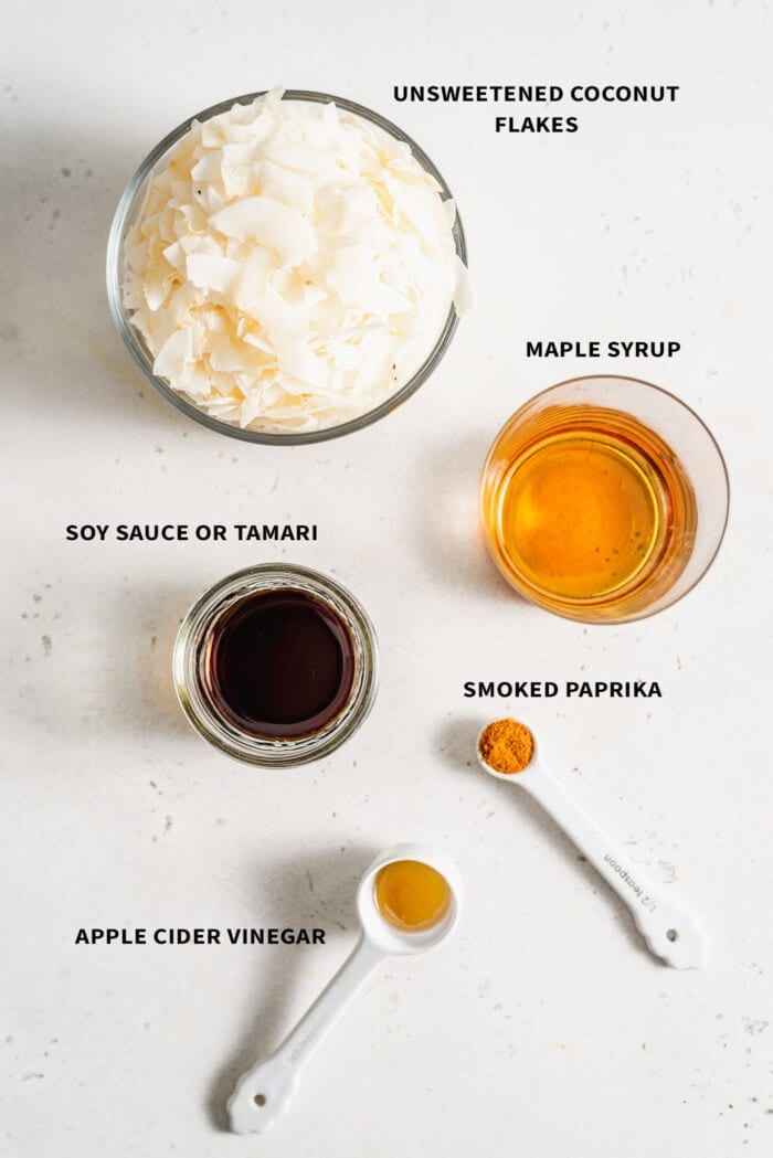 Ingredients needed to make coconut bacon: maple syrup, soy sauce, paprika, coconut flakes and apple cider vinegar.