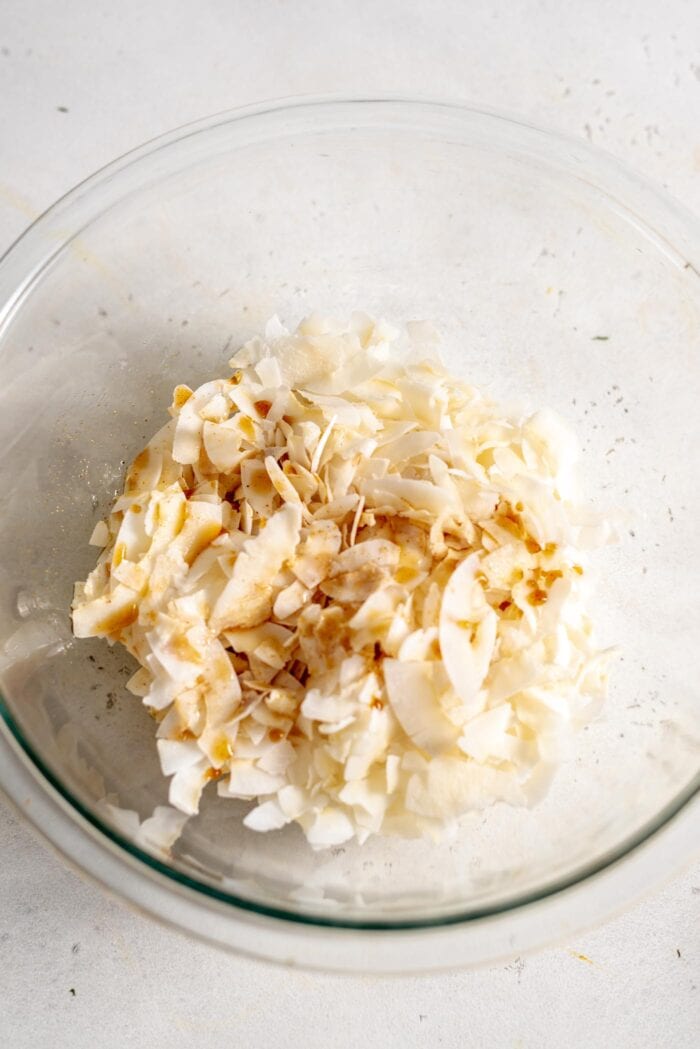 A bowl of coconut flakes with a marinade poured over it.