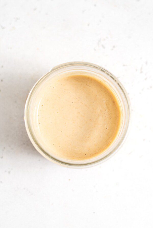 Creamy miso tahini dressing in a small glass jar.