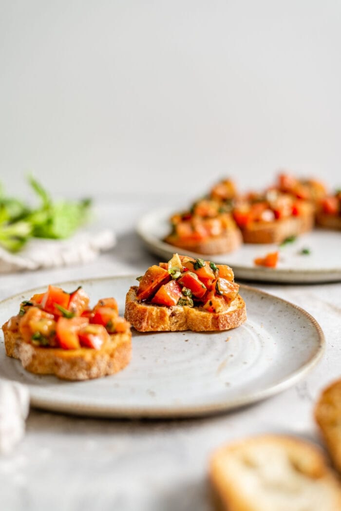 A slice of toasted baguette topped with a mixture of tomato and basil.
