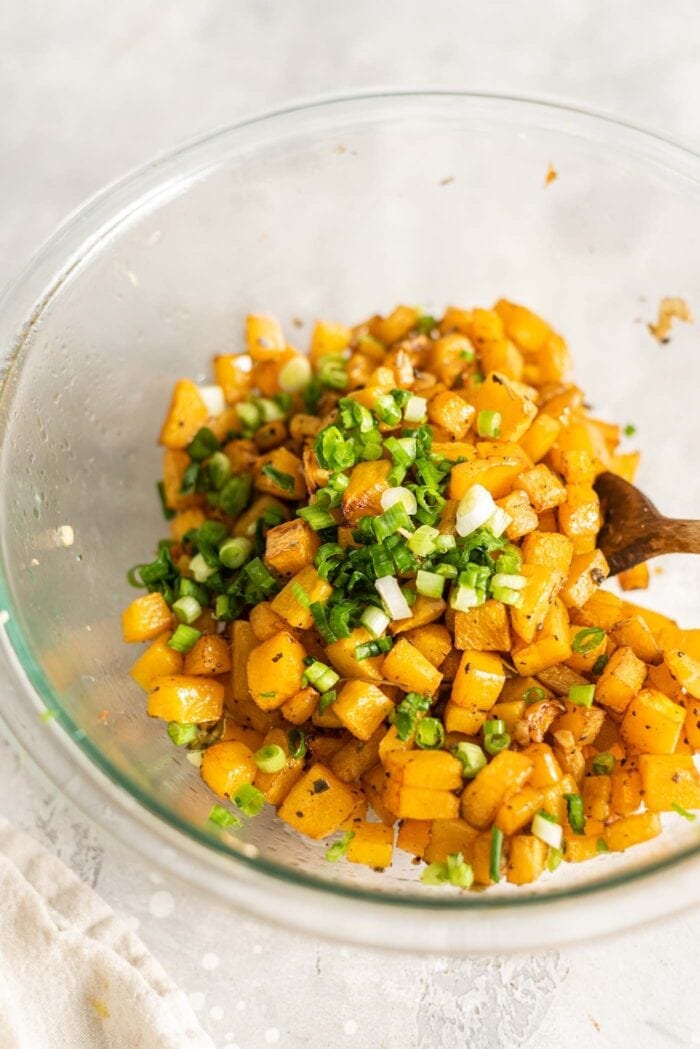 Roasted butternut squash and green onion in a mixing bowl.
