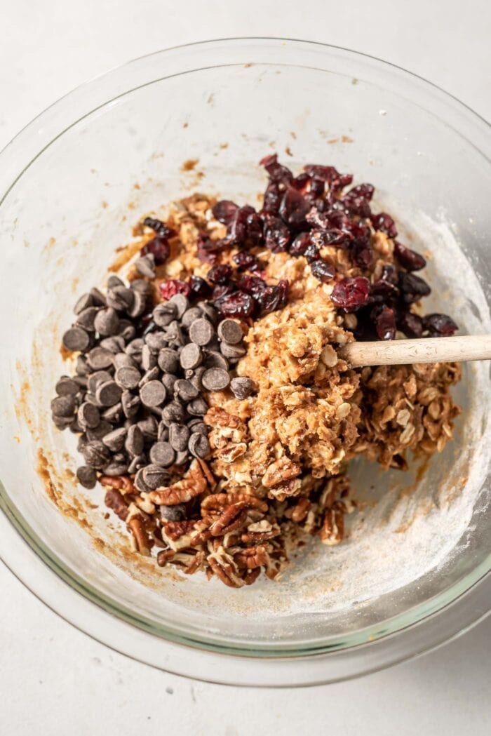 Raw cookie batter with cranberries, chocolate chips and pecans being mixed in.