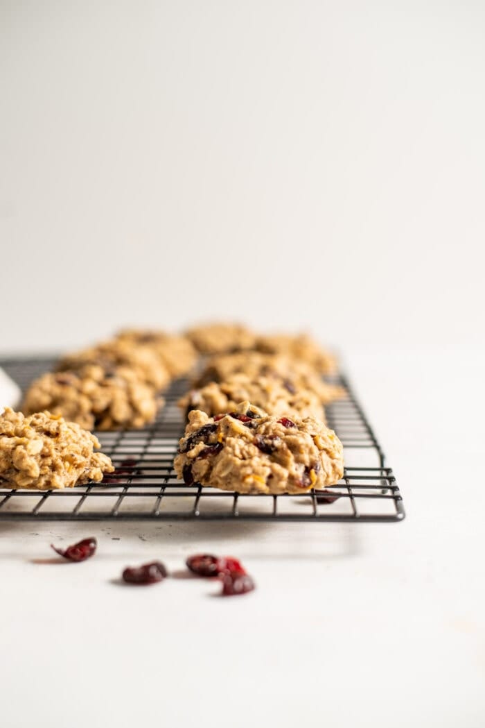 A number of cranberry oatmeal cookies on a baking cooling rack.