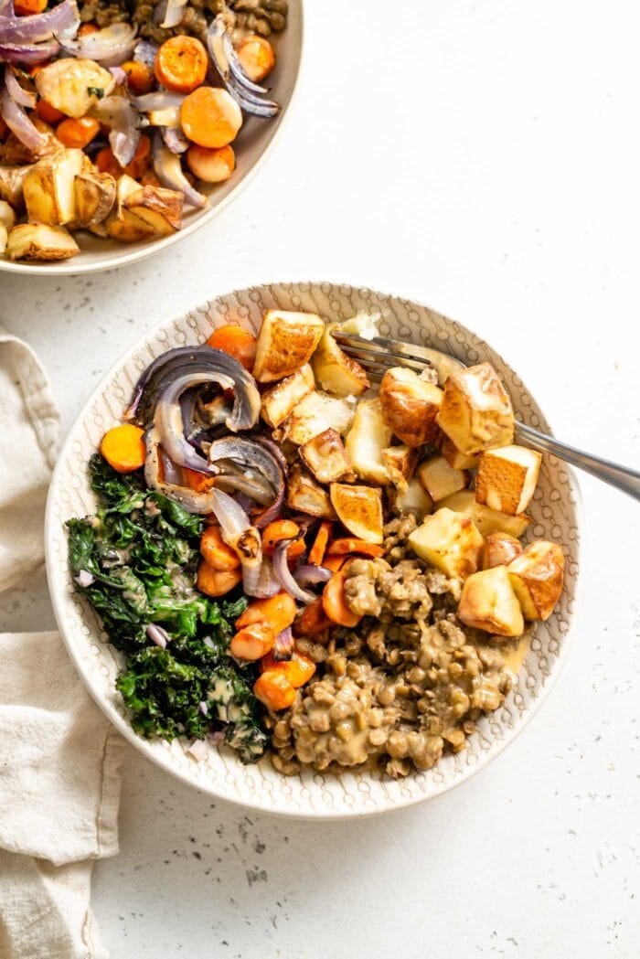 Roasted potatoes, lentils, carrots, onion and kale in a bowl topped with vegan miso gravy.
