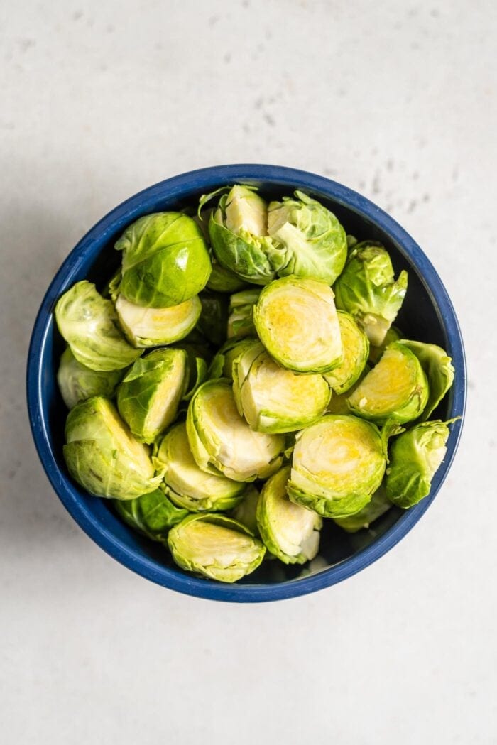 Chopped raw brussels sprouts in a measuring up sitting on a white surface.