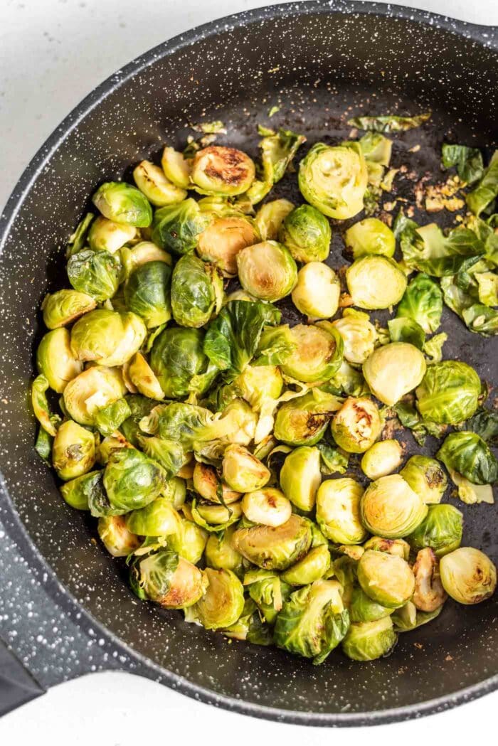 Sauteed Brussels sprouts in a black skillet.
