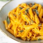Bowl of creamy pumpkin penne topped with fresh sage.