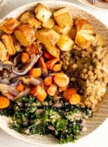 Bowl of roasted veggies, kale and lentils with sauce.
