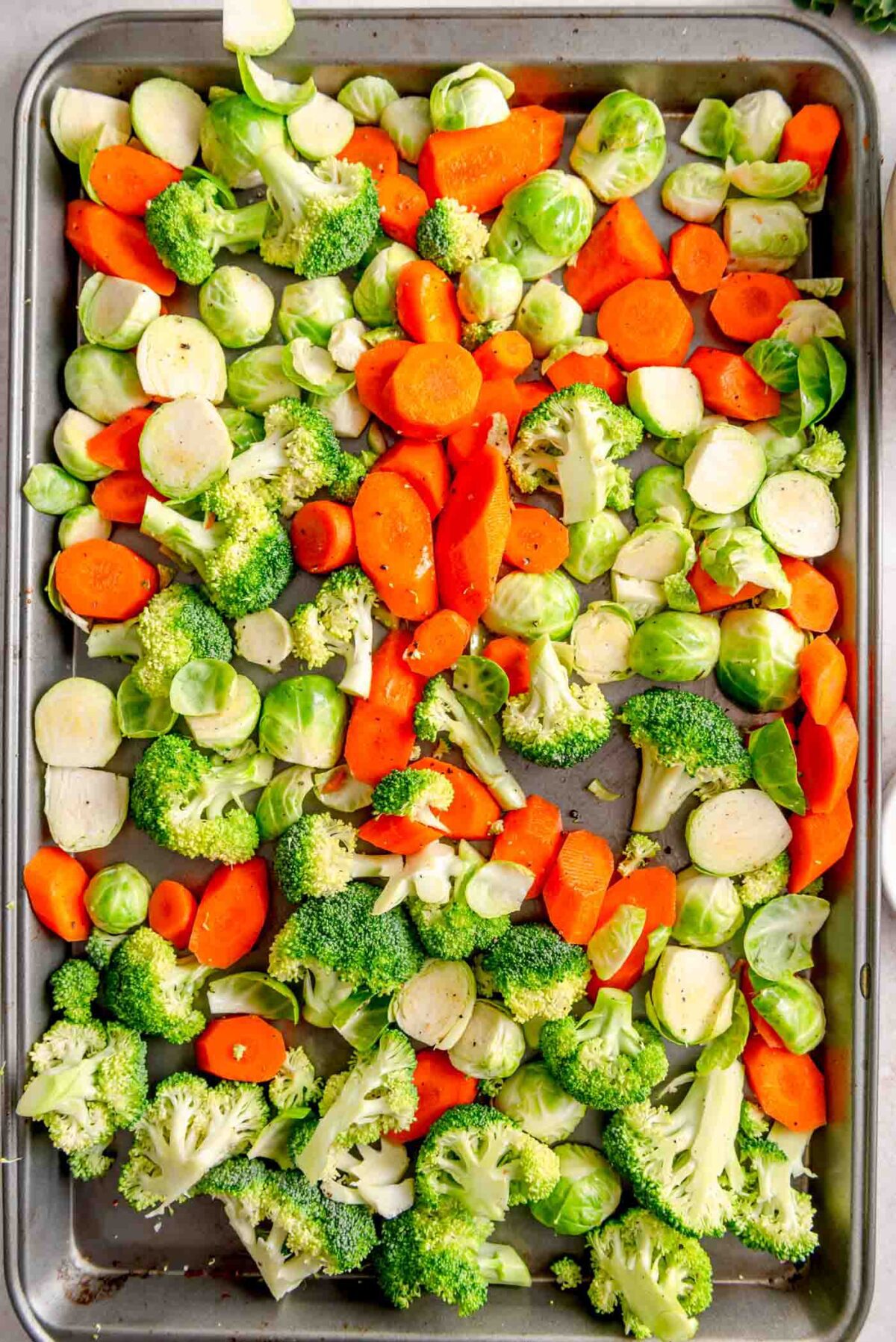 Chopped Brussels sprouts, carrots and broccoli on a large cutting board.