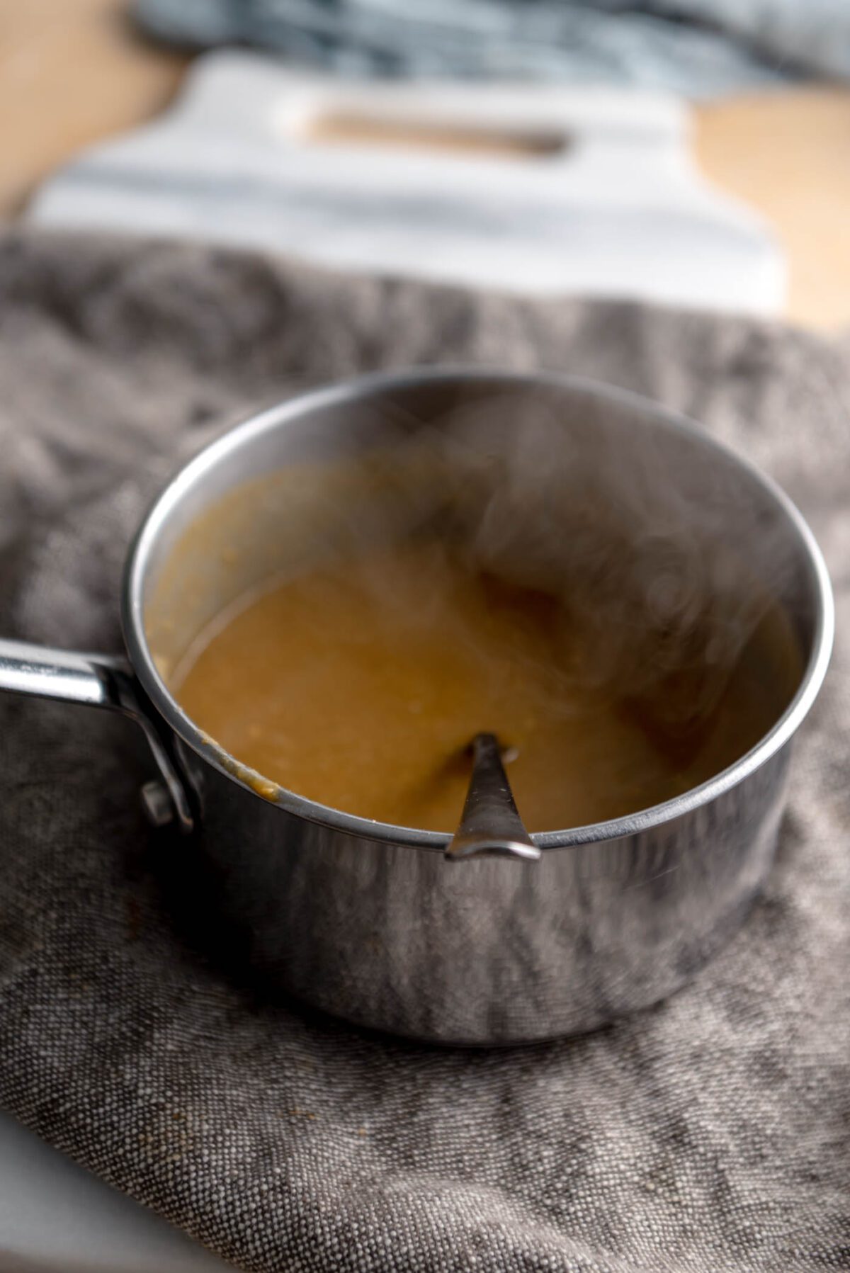 Gravy cooking in a small pot with a spoon in it.