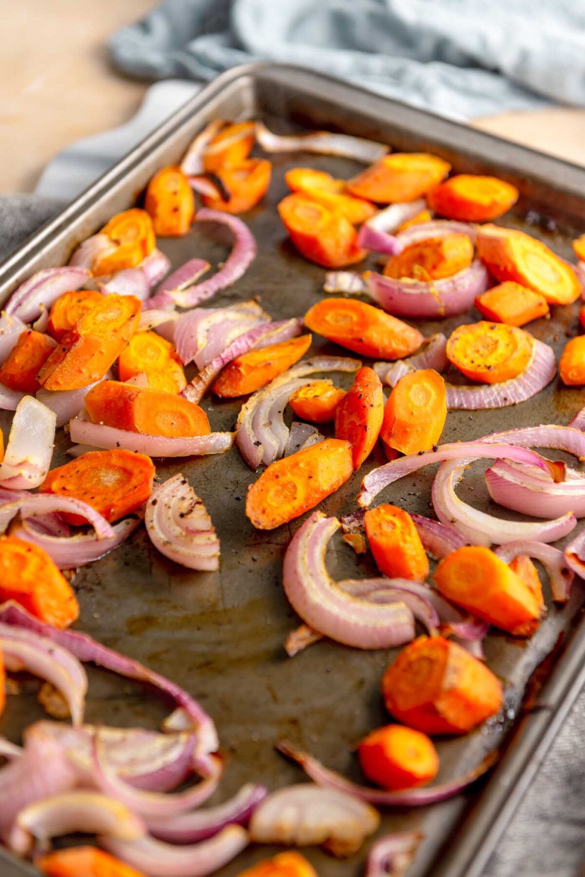 Chopped onion and carrot on a baking sheet.