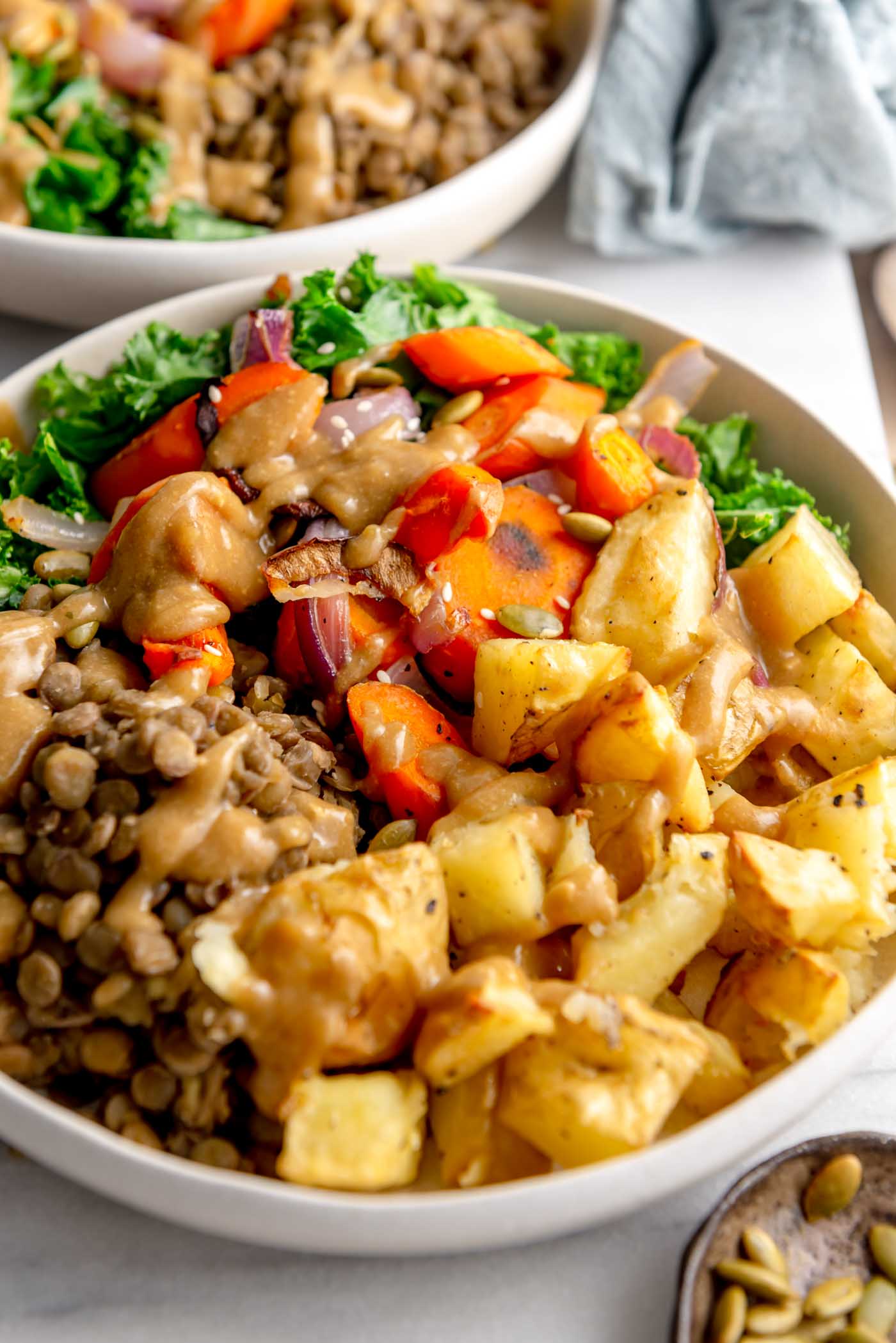 Healthy vegan bowl with roasted potatoes, roasted onion and carrot, lentils, kale and gravy.