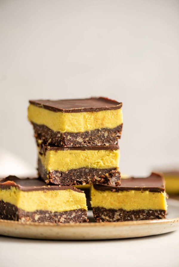 A stack of no-bake vegan Nanaimo Bars on a small plate.