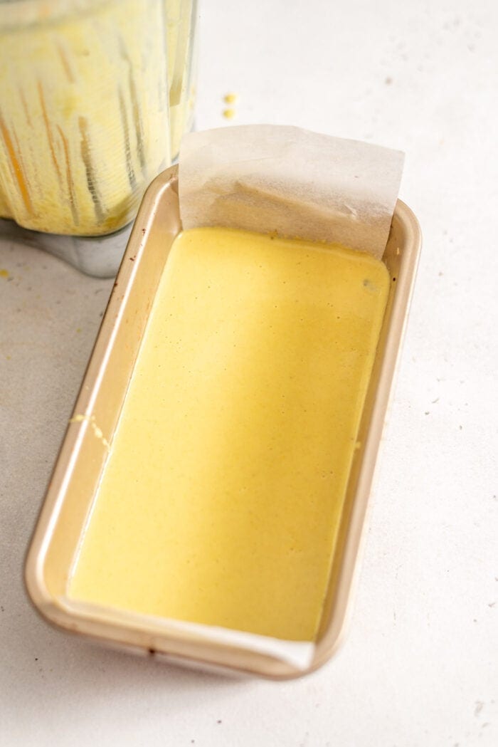 The custard layer for Nanaimo Bars in a loaf pan lined with parchment paper.