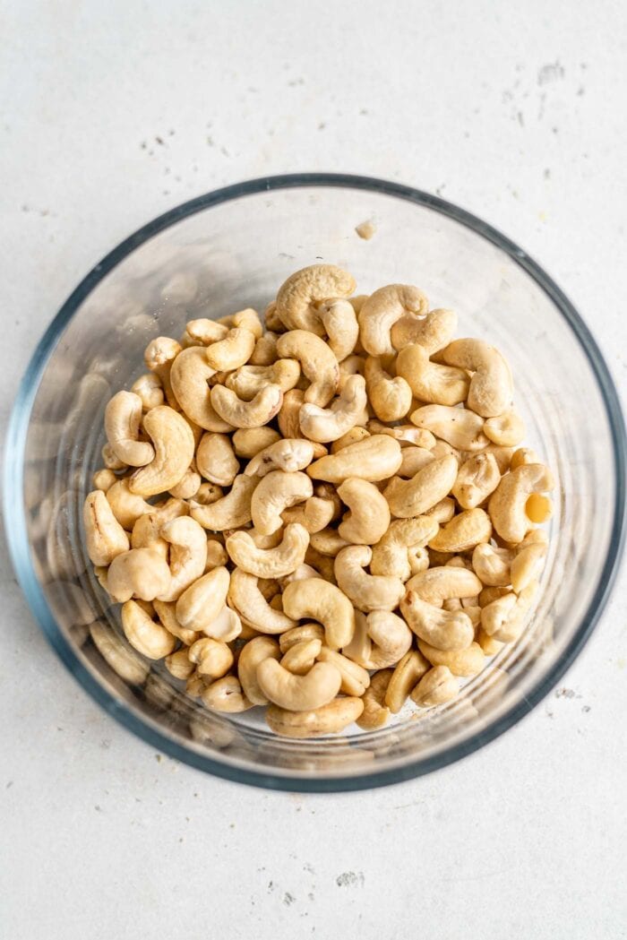 Raw cashews in a glass bowl.