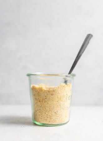 Vegan parmesan cheese in a jar with a spoon.