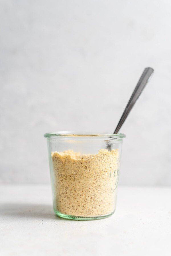 Vegan parmesan cheese in a jar with a spoon.