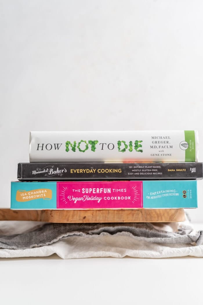 3 vegan books sitting on a block of tofu wrapped in a dish cloth.
