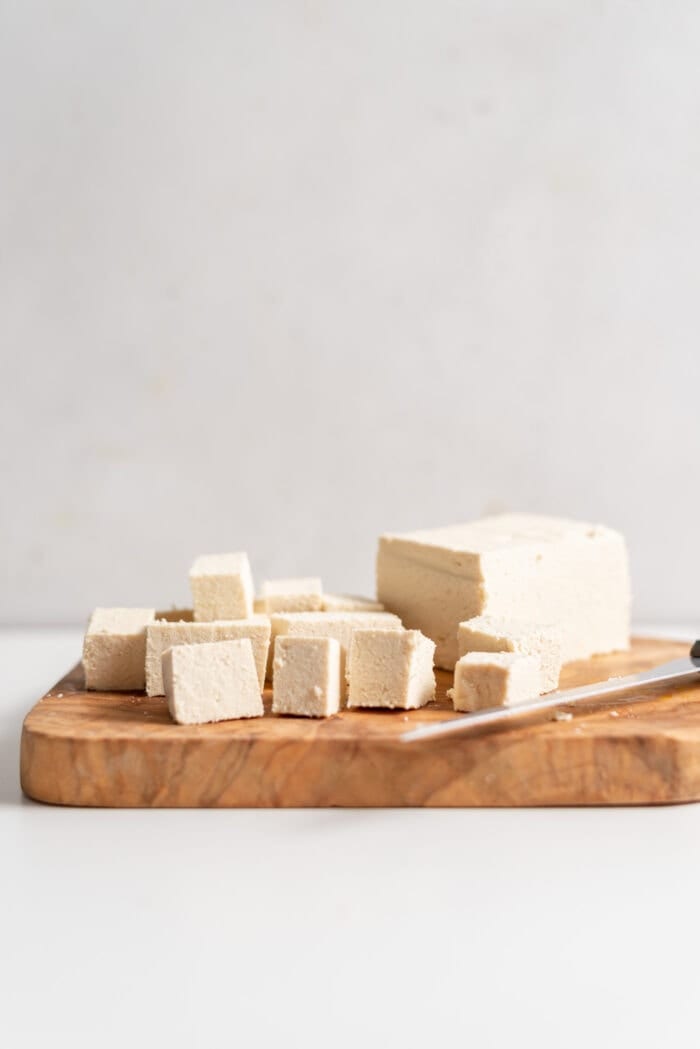 Cubed tofu on a cutting board with a knife