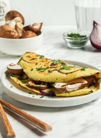 Chickpea flour omelette stuffed with mushroom and onions on a plate.