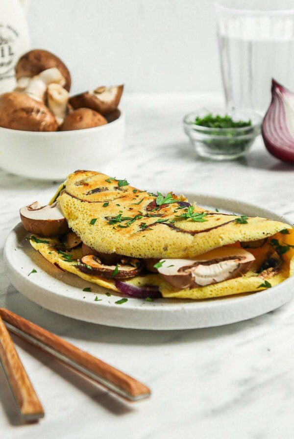 Chickpea flour omelette stuffed with mushroom and onions on a plate.