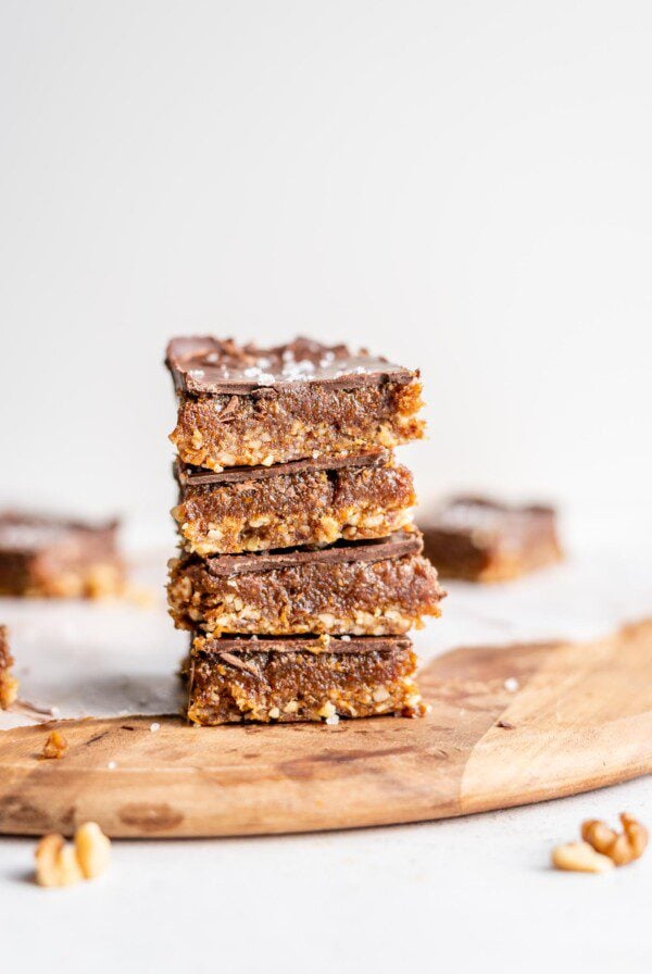 A stack of 4 chocolate caramel bars on a cutting board.