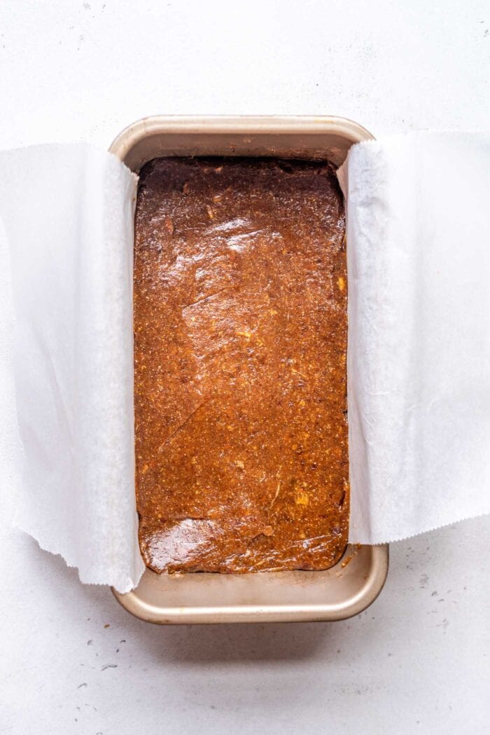 Date caramel spread in a loaf pan lined with parchment paper.